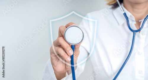 Annual health checkup concept with female doctor using diagnosis stethoscope with shield icon for preventive screening. Early detection and risk assessment for future diseases and treatment planning.