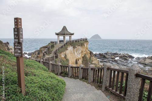 Traditional Chinese pavilion and concrete pathway along the coastal cliffs at Heping Island Park with Keelung Islet in the distance, Taiwan.