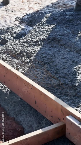 Construction workers are pouring fresh concrete to form foundation, with leveling surface cement slab