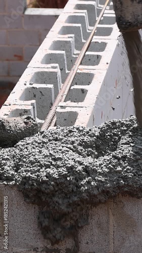 Construction worker fills blocks with concrete while building foundation using cement pump