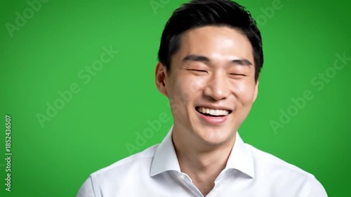 Smiling Asian man in white shirt against a bright green backdrop, close up portrait