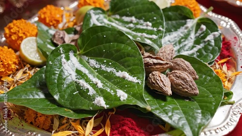 Traditional Offering Tray With Green Betel Leaves And Orange Marigolds Sprinkled With White Powder And Spices In Natural Light