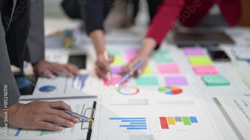 A group of people are working on a project and writing on a white board. There are many different colored sticky notes on the board