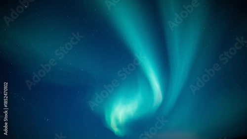 Wispy, vertical pillars of emerald and cyan light illuminate the dark expanse of space, creating a sense of motion and celestial wonder.