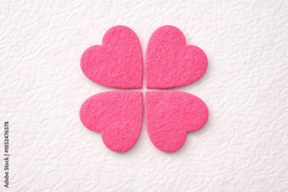 Fototapeta premium pink felt hearts in a clover design isolated on a textured flat lay background. abstract 3d valentine's day design element.