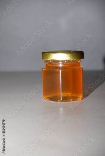 Close-up of mini hexagonal glass jars with pure honey and gold lids for wedding favors and event souvenirs