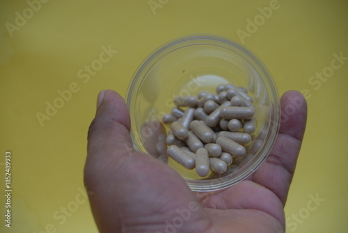 Hand holding a transparent container with herbal medicine capsules