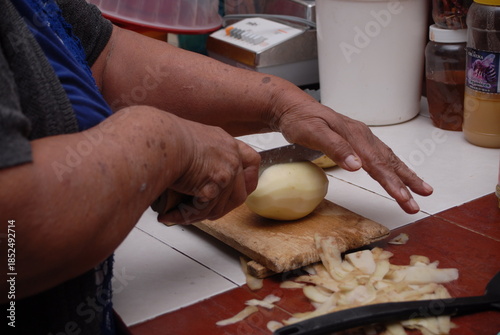 Traditional preparation of Mexican potatoes with chorizo and fresh green salsa using a volcanic stone mortar (molcajete)