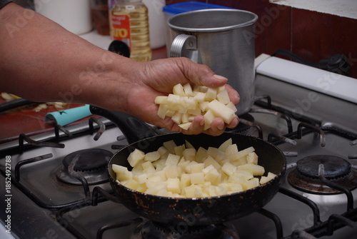 Traditional preparation of Mexican potatoes with chorizo and fresh green salsa using a volcanic stone mortar (molcajete)