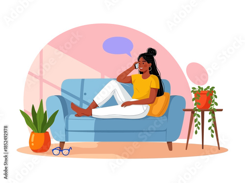Woman sitting on a couch talking on a phone with plants nearby