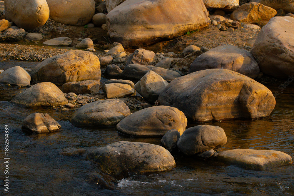 Obraz premium A massive rock along a riverside forming a serene natural backdrop. This image represents stability, silence, and harmony within nature.
