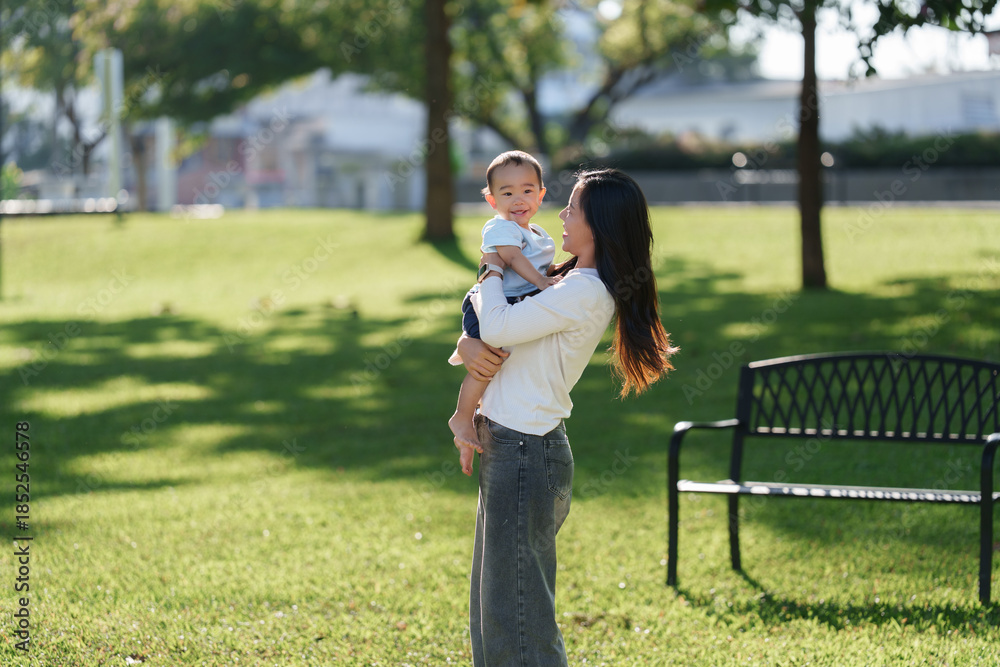 Fototapeta premium Loving mother holding happy baby boy in park