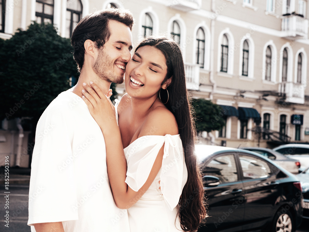Fototapeta premium Smiling beautiful woman and her handsome boyfriend. Happy cheerful family. Sexy couple posing in the street at sunrise. During romantic date at sunny summer day outdoors. Looking at each other
