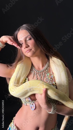 Performance with a snake by a dancer in an indoor setting at a cultural event during the evening hours