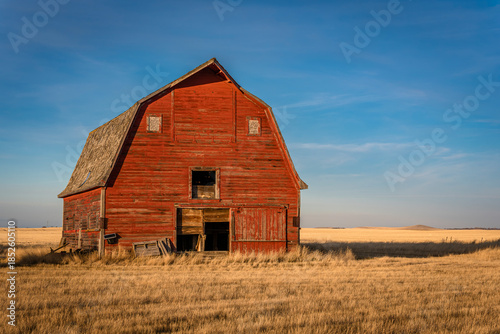 Golden light on a large abandoned red barn on the prairies in Saskatchewan