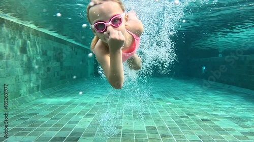 Swimming practice of a child in a pool with goggles in warm water