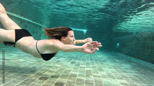 Swimming underwater in a pool, showcasing diving and swimming skills