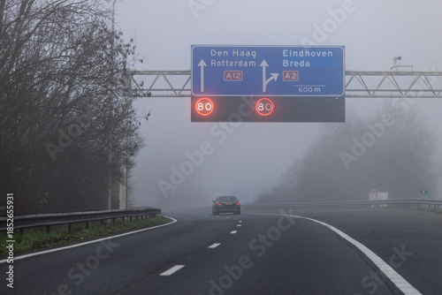 Obraz na plátně A misty highway scene in the Netherlands with overhead matrix signs displaying an 80 km/h speed limit on the A12 towards Den Haag and Rotterdam