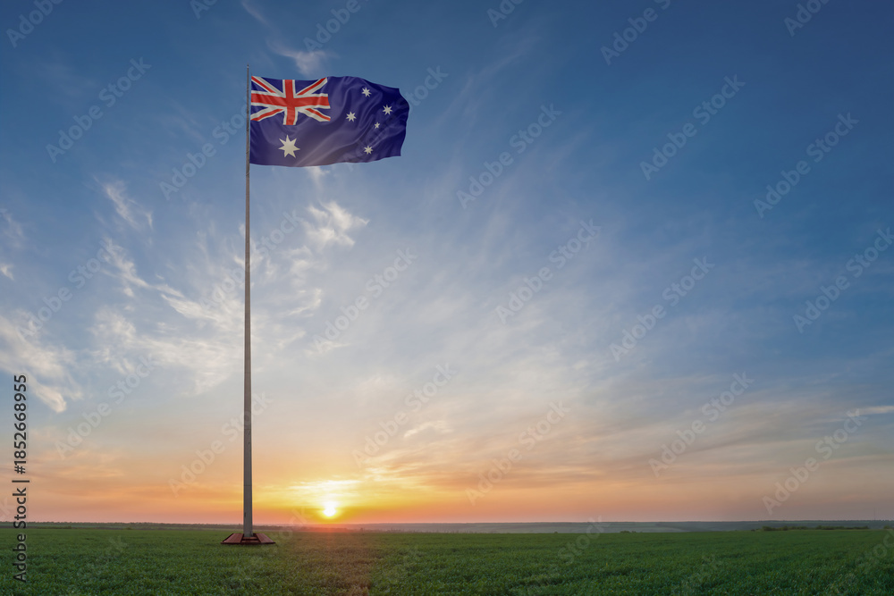 Fototapeta premium On flagpole in green field waving National flags of Australia