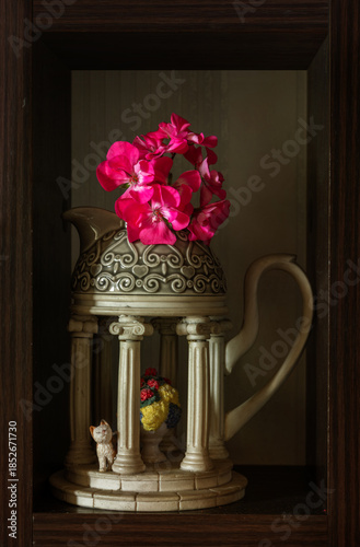Still life with blooming geraniums in a ceramic milk jug.