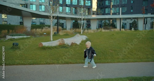 Toddler walking alone in modern residential park