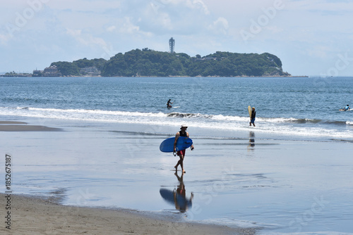 潮が引いた片瀬西浜海岸で海に入るサーファー