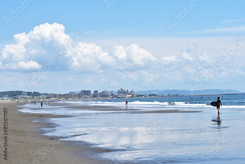 潮が引いた片瀬西浜海岸で海に入るサーファー