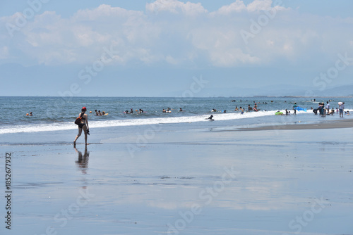 潮が引いた片瀬西浜海岸で海に入るサーファー