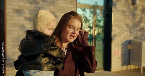 Mother holding baby near apartment building entrance