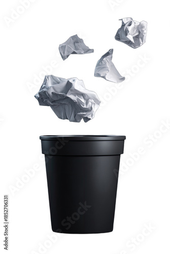 Crumpled paper balls tossed into a black trash can against a black background