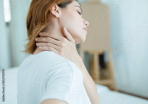 The young woman experienced body aches while sitting on the bed. She felt pain and stiffness in her shoulders, neck, and back, along with muscle spasms and general discomfort.