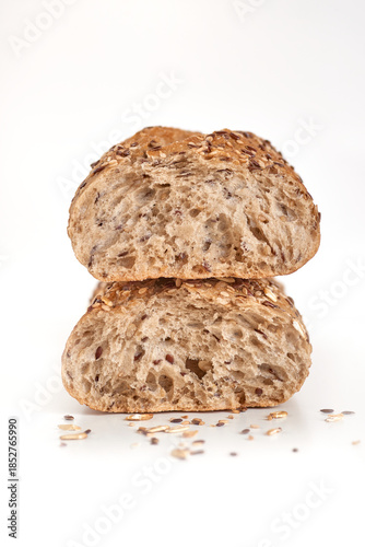 Macro photo of whole grain baguette cut with different seeds lying on a white table