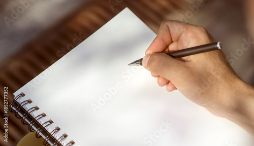 A man is doing notes, holding a notebook and a pen in his hands.