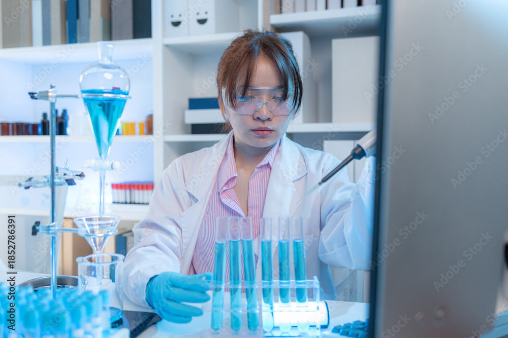 Fototapeta premium A chemistry researcher in a laboratory surrounded by scientific equipment and test tubes, representing innovation, scientific development, and modern medical research environment.