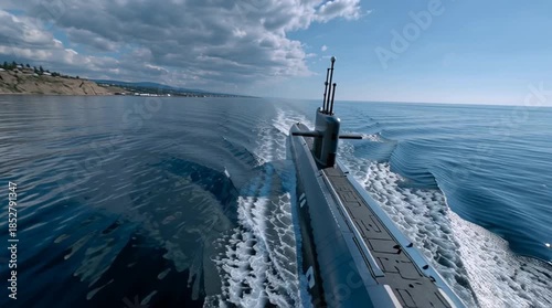 A modern submarine sails along a picturesque coastline. The view from the deck is of sea waves and coastal cliffs.