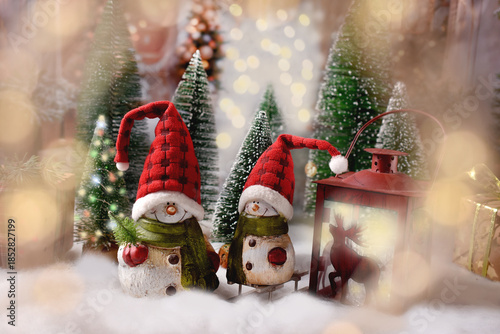 Christmas winter scene with two snowman figurines in Santa hat standing outdoor in the snow