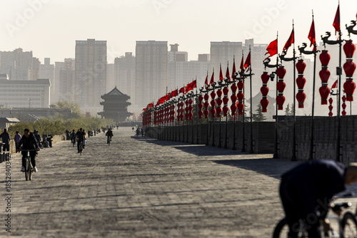 View of ancient brickwork underfoot, red lanterns fluttering above, and modern buildings fading into the horizon's haze, Xi'An, Shaanxi, China.
