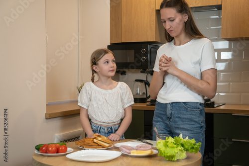 Mother and daughter bonding in a modern kitchen, learning to prepare healthy sandwiches together for breakfast or lunch, smiling and sharing hands-on family cooking time