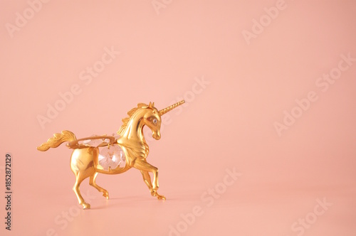 A unicorn figurine on a pink background.
