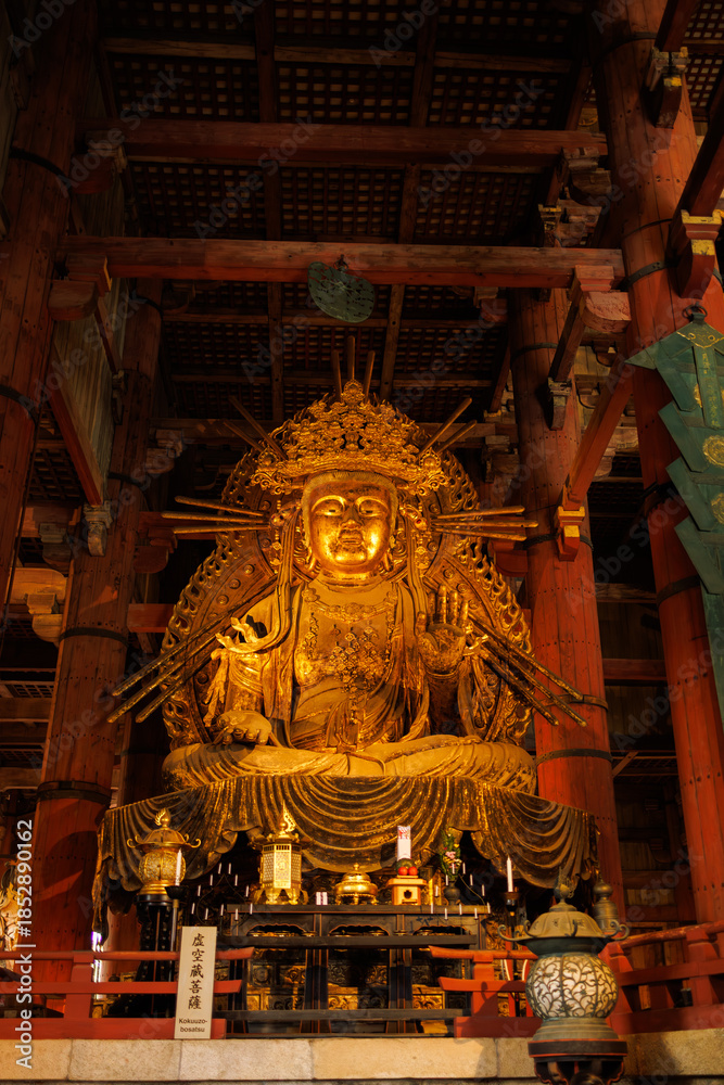 Obraz premium Golden Buddha Statue Inside Traditional Temple Hall With Ornate Backdrop And Wooden Ceiling. Nara City, Japan