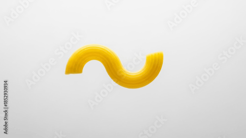 Single piece of uncooked yellow cavatappi pasta isolated on white.