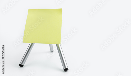 Blank yellow note paper on a tripod. Important message reminder