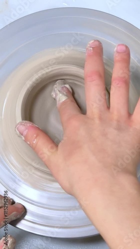 Child making ceramic vase on rotating pottery wheel at workshop. Creativity and traditional crafts concept.
