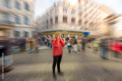 Blond woman is having stress, anxiety, fear or panic attack in public. Mental health disorder. Phobia of crowd of people. Schizophrenia, agoraphobia or paranoia. Blurry busy city street.