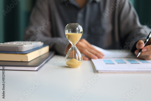 Selective focus on Sand Clocks. Businessman working at office desk. Time management concept.