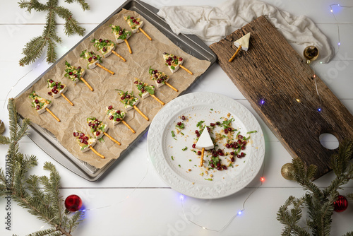 Tree shaped brie cheese appetizers with pomegranate, walnuts, cilantro and a pretzel stick