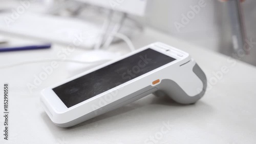 Pay by phone on electronic payment machine or card reader. E-money at cashless wallet. Female hand with pos-terminal and cellphone closeup. Client pays for the procedure in modern beauty clinic.