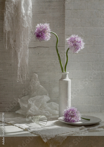 Still life with flowering onions in a white vase on a light background