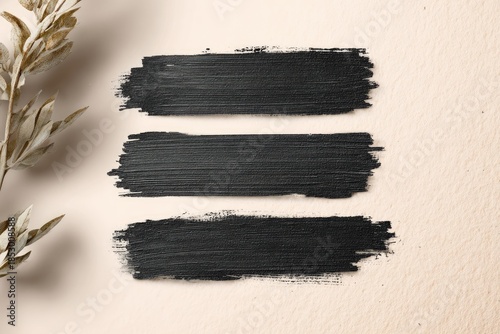 Black paint strokes on a textured, light beige background with dried floral accent