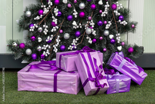 Christmas tree detail with purple ornaments decoration and presents beneath